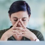 Bir çalışan, işyerindeki stresle başa çıkmak için derin nefes alarak rahatlamaya çalışıyor.