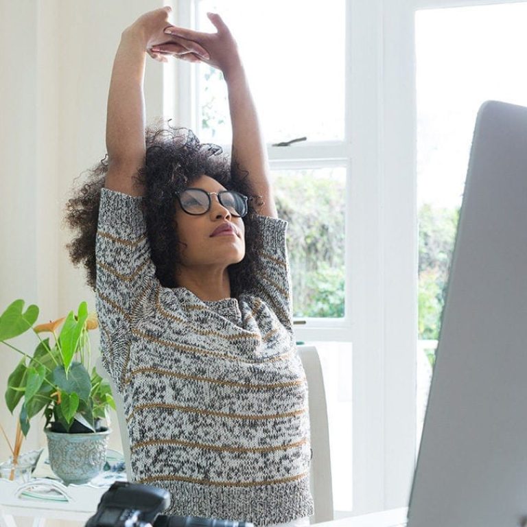 Çalışan bir kişinin ofiste, stresle başa çıkmak için uyguladığı rahatlama teknikleriyle sakinleşmesi.
